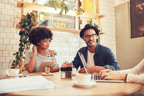 Group of friends sitting in a coffee shop with laptop