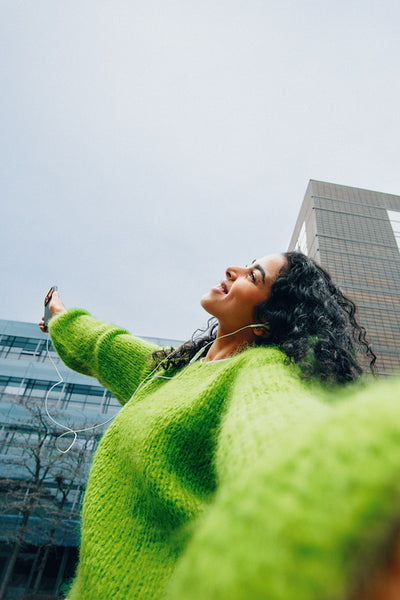 Smartphone in hand, the woman enjoys music with headphones on a city walk