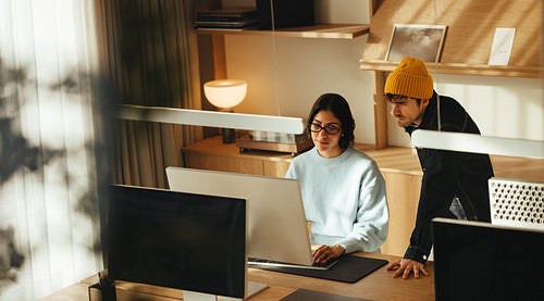 Coworkers review work on a computer in the office
