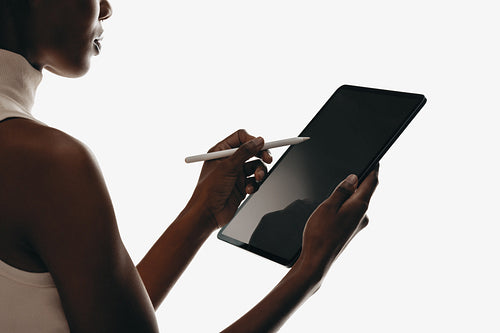 Woman using stylus on digital tablet with blank screen for mockups