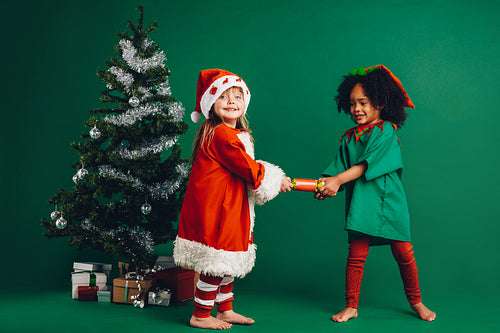 Little girls standing near a christmas tree holding a toy