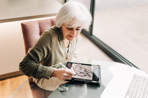 Mature graphic designer drawing on a digital tablet