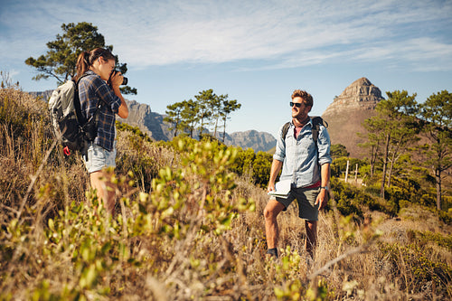 Woman taking a picture of boyfriend outdoors in nature