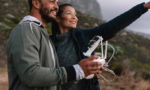 Young couple flying drone outdoors in countryside