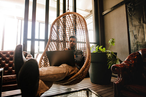 Man relaxing in office lounge with laptop
