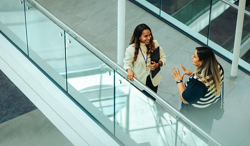 Female colleagues having a corporate discussion in office atrium