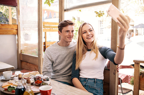 Couple taking photos of themselves in cafe