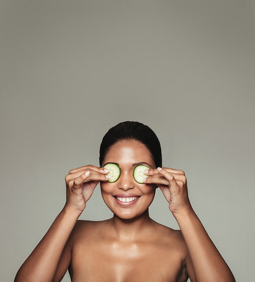 Woman holding cucumber over eyes