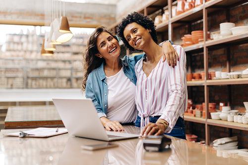 Happy ceramic shop owners embracing each other in their store