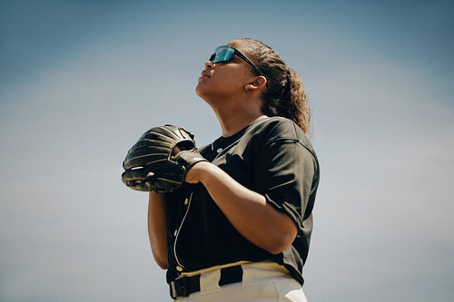 Confident female baseball player in uniform looking up with determination
