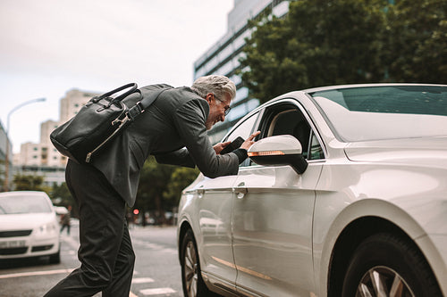 Mature businessman talking to taxi driver