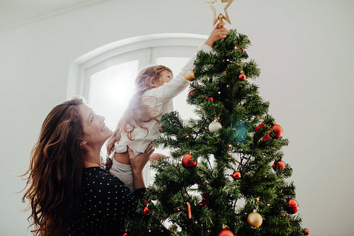 Mother and child decorating Christmas tree.
