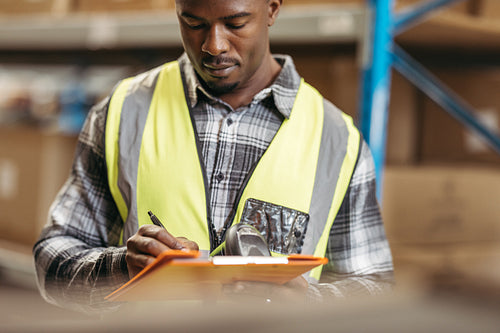 Logistics worker recording inventory in a warehouse