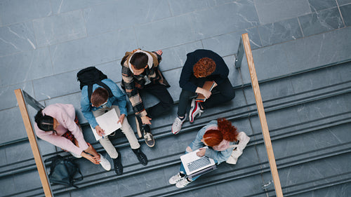 Group project on a campus: College students having a discussion as they work on a assignment together