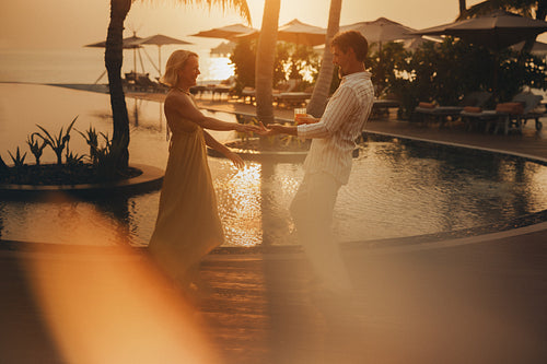 Couple dancing backlit by the sunset at a tropical resort, enjoying romantic moment
