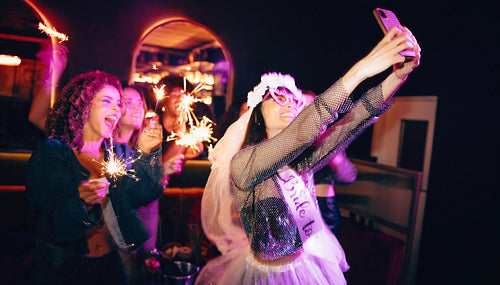 Women celebrating a bachelorette party holding sparklers in a lively atmosphere