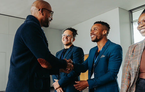 Coworkers shaking hands and smiling in a modern office setting