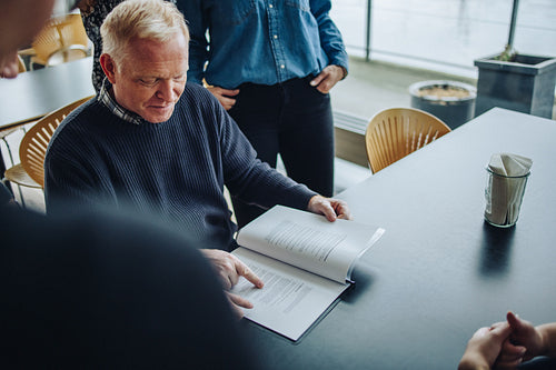 Businessman reading contract document for colleagues