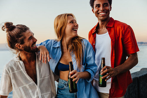 Joyful friends relaxing by the sea during a summer evening