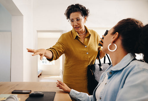 Female business owner briefing employee in a modern workplace setting