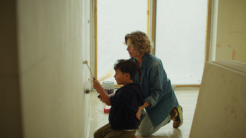 Creating memories: Mother and son paint a wall together during home renovation