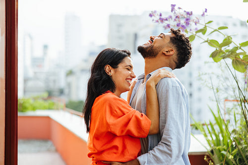 Young couple laughing together outdoors on a sunny day