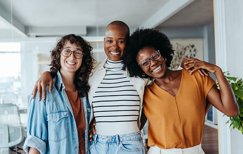 Group of three business women smiling happily in an office