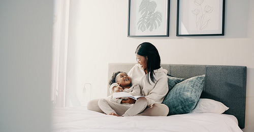 Story time, little girl laughing with her mom while reading a book