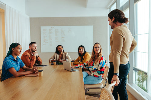 Caucasian businessman addressing diverse colleagues in a meeting room