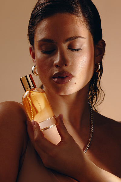 Woman holding perfume bottle close to chest