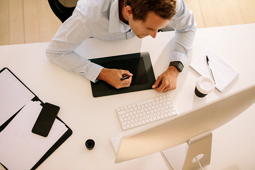 Top view of man using digitizer to write text in computer