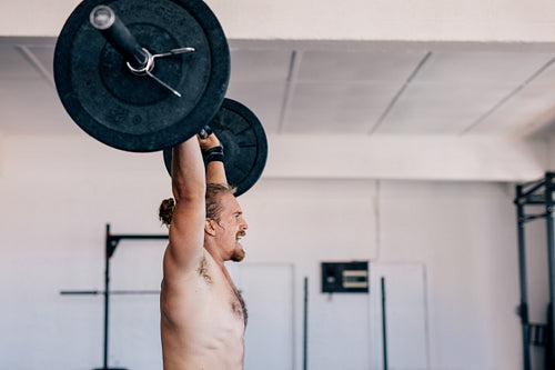 Muscular man lifting heavy barbell at gym