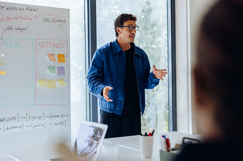 Male designer explains UX plan beside whiteboard