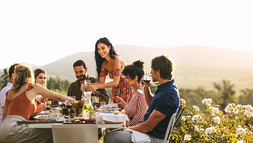 Woman serving food to friends at dinner party