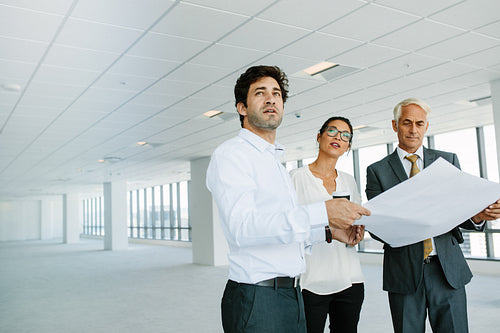 Estate agent and clients with blueprints of new office space