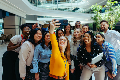 Happy colleagues taking a group selfie in a modern office