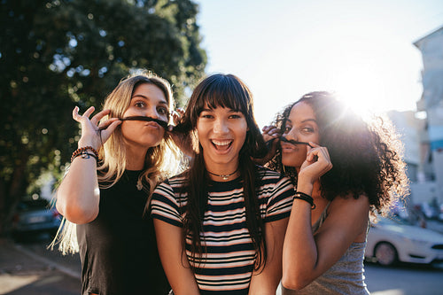 Young women make faces with mustache made of hair