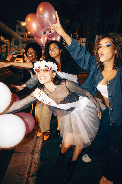 Young women celebrating a bachelorette party with balloons during a night out