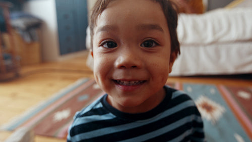 Happy young boy laughing with his face zooming into the camera at home