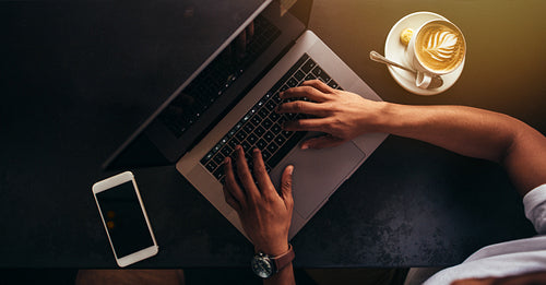 Close up of man at coffee shop working on laptop
