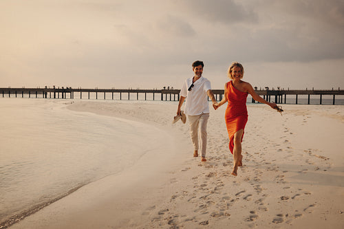 Mature couple enjoying a romantic walk on a beach island at sunset