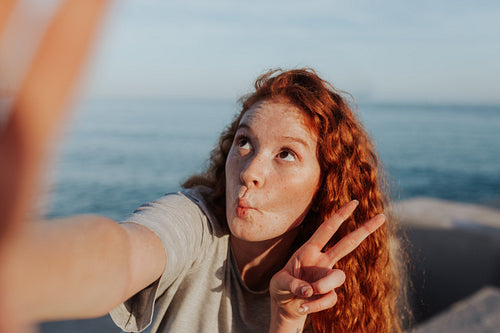 Carefree young woman taking a selfie next to the sea