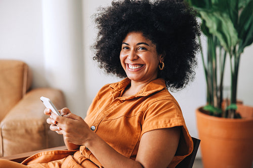 Businesswoman smiling cheerfully while holding a smartphone