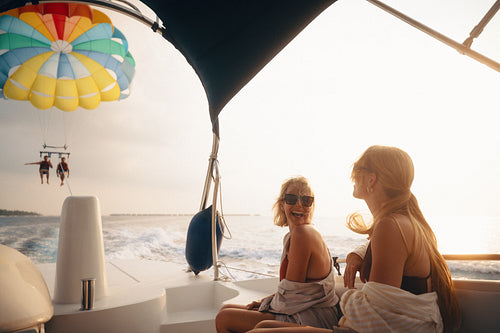 Joyful vacation activity with friends on a boat, enjoying parasailing at sunset