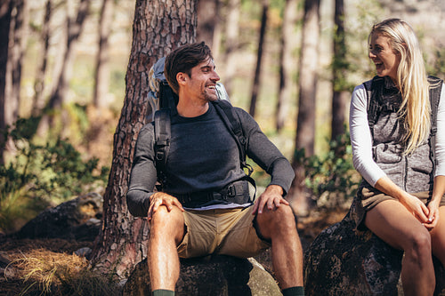 Hiking couple relaxing sitting on rocks during trekking