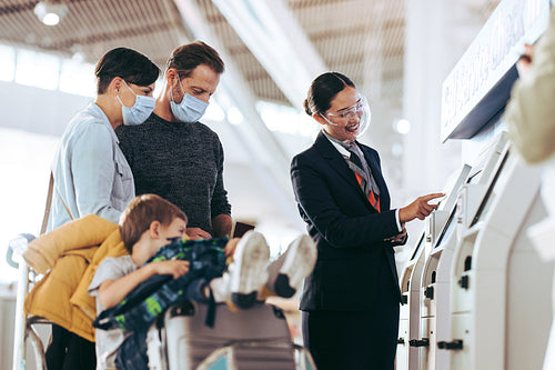 Airport staff helping family with self check in