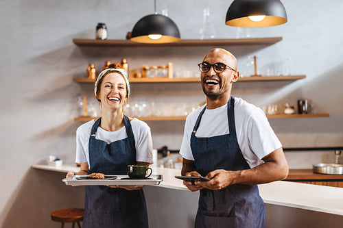 Baristas smiling happily at work, ready to serve customers