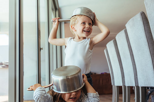 Children playing knight with kitchen utensil