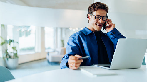 Man on phone with laptop in work setting