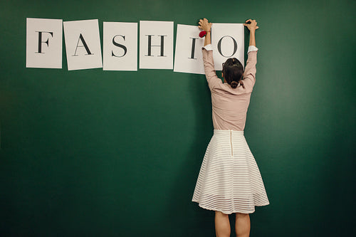 Woman arranging fashion word alphabets on wall